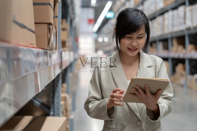 女商人使用数码平板电脑检查工厂配送仓库货架上的库存产品库存数量